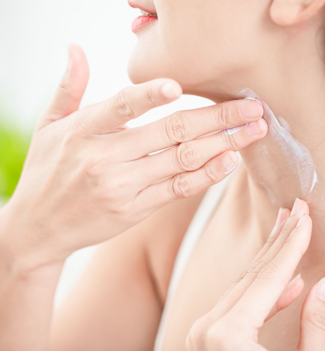 Woman applying cream to her neck and chest