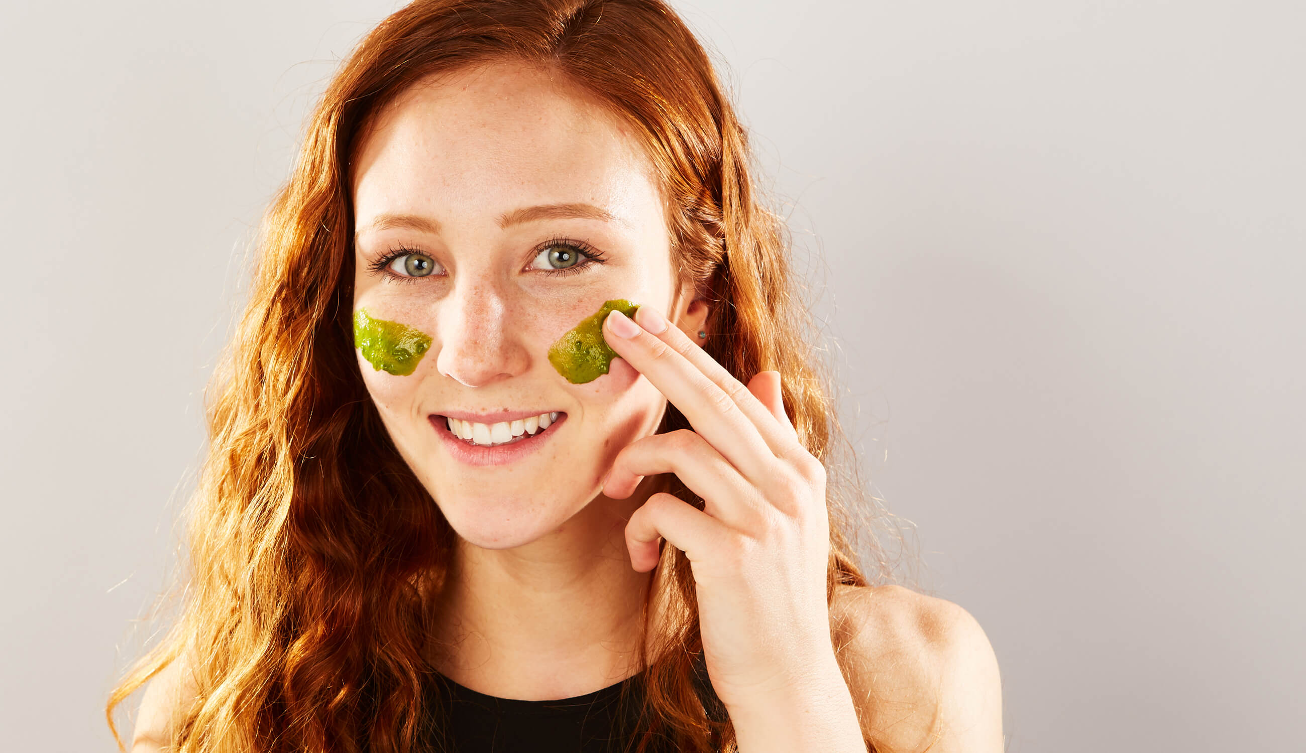 Woman using 100% PURE Green Tea Mask on her face