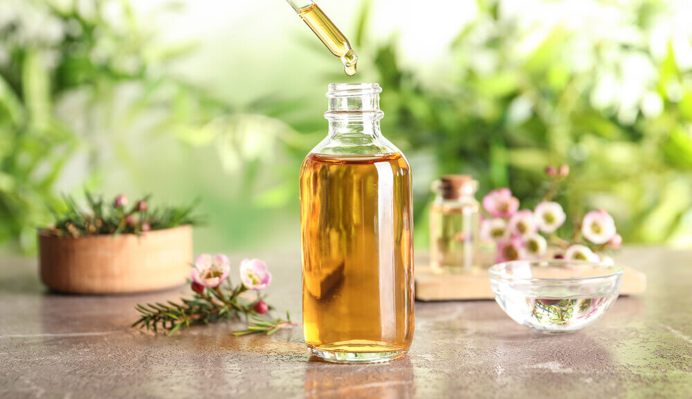 Aceite esencial para cicatrices con gotero rodeado de flores.