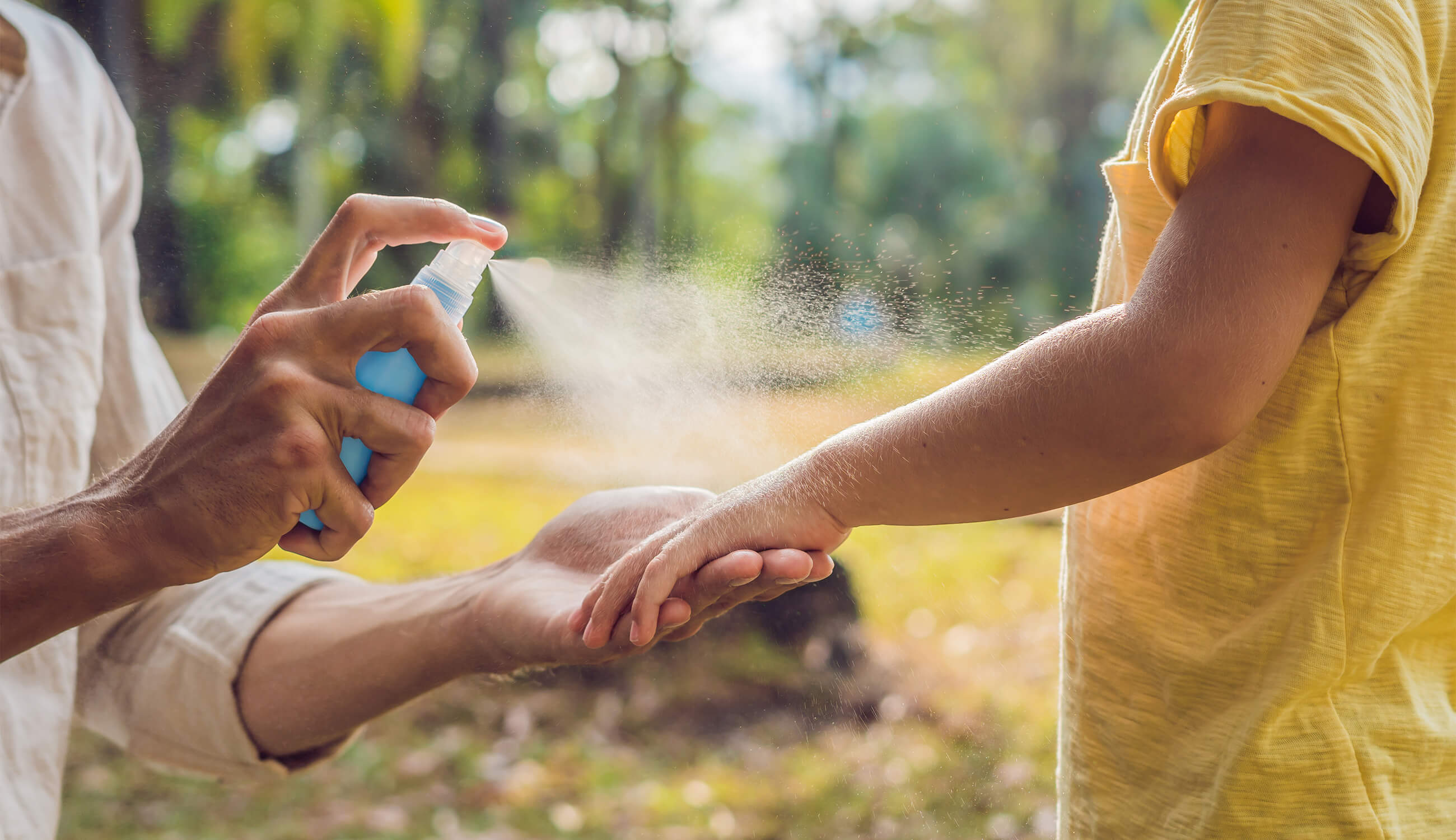 Main_spraying insect repellent on skin outdoor