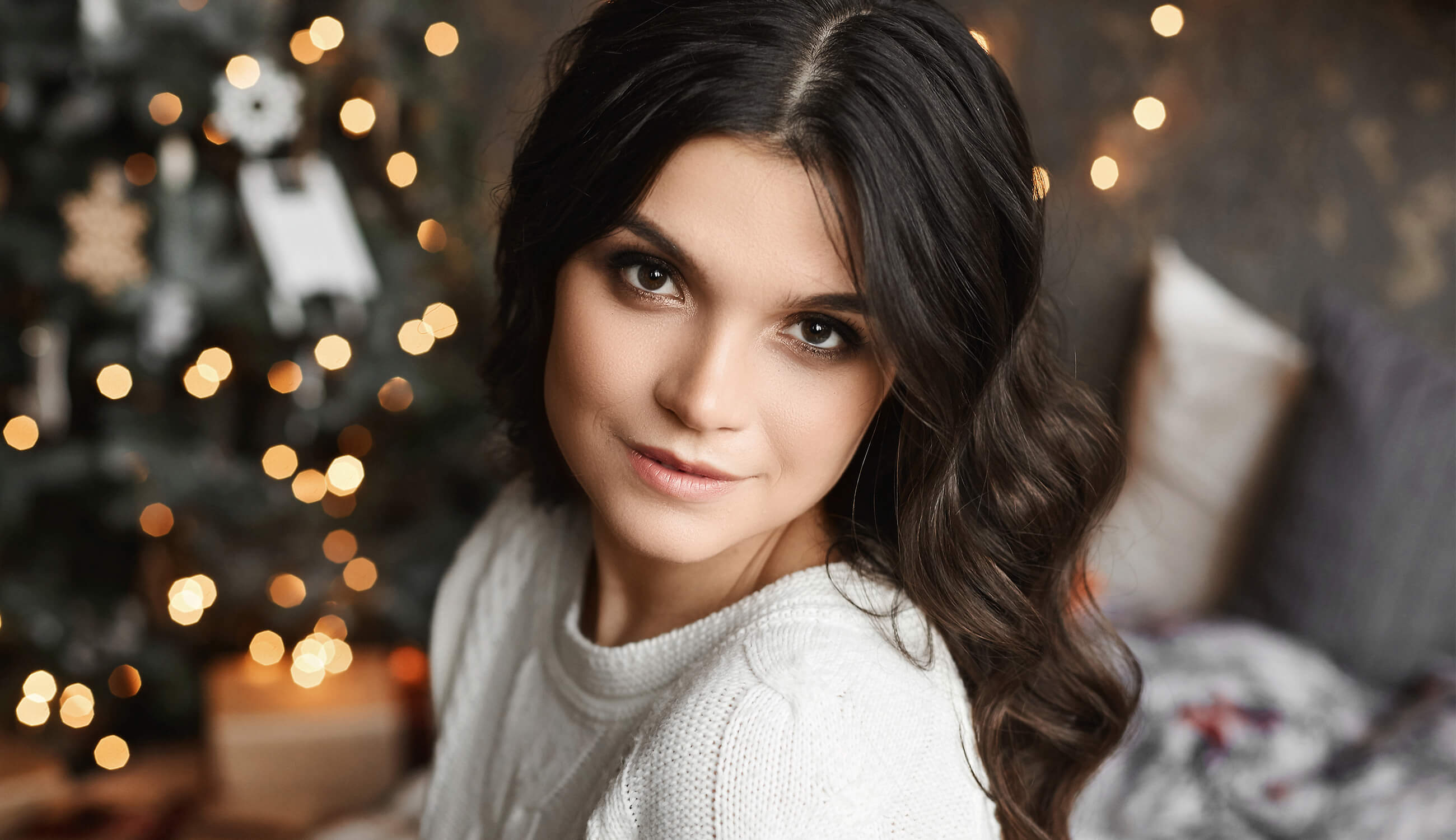 Main_smiling woman posing in an interior with festive Christmas lights