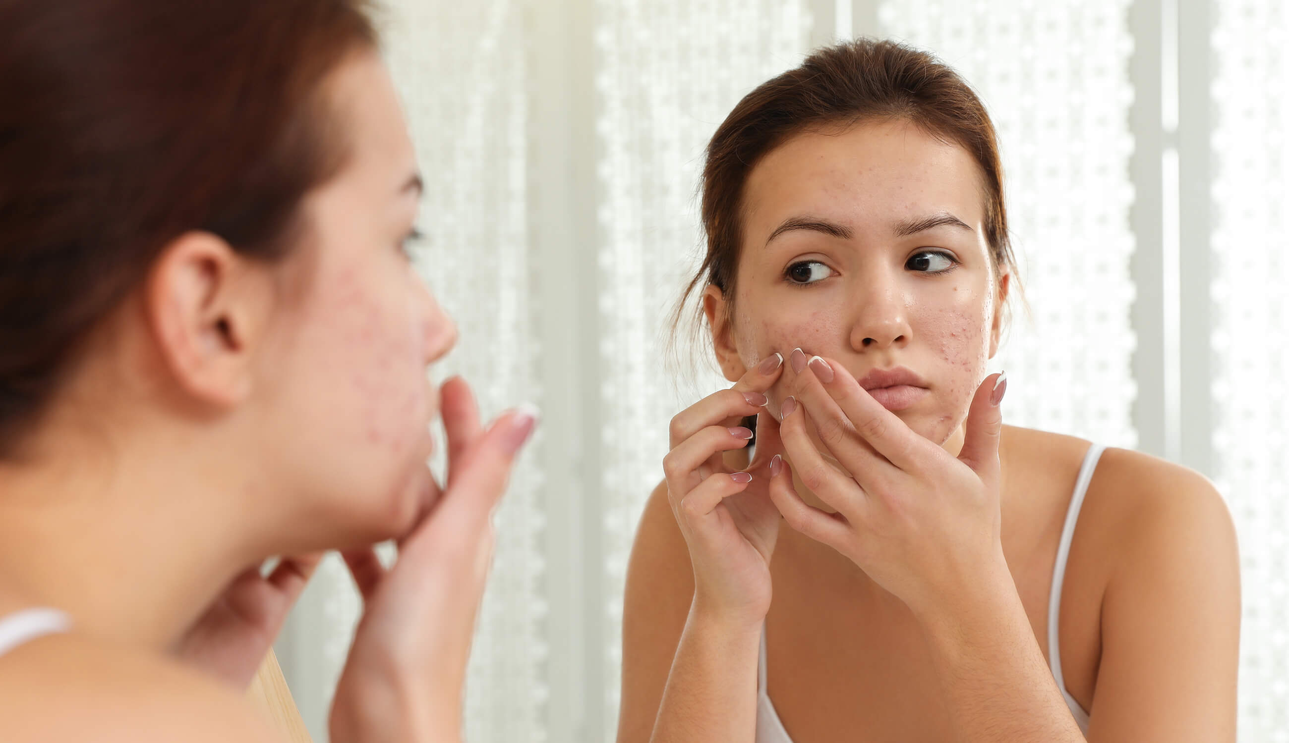 Main_woman inspecting face in mirror