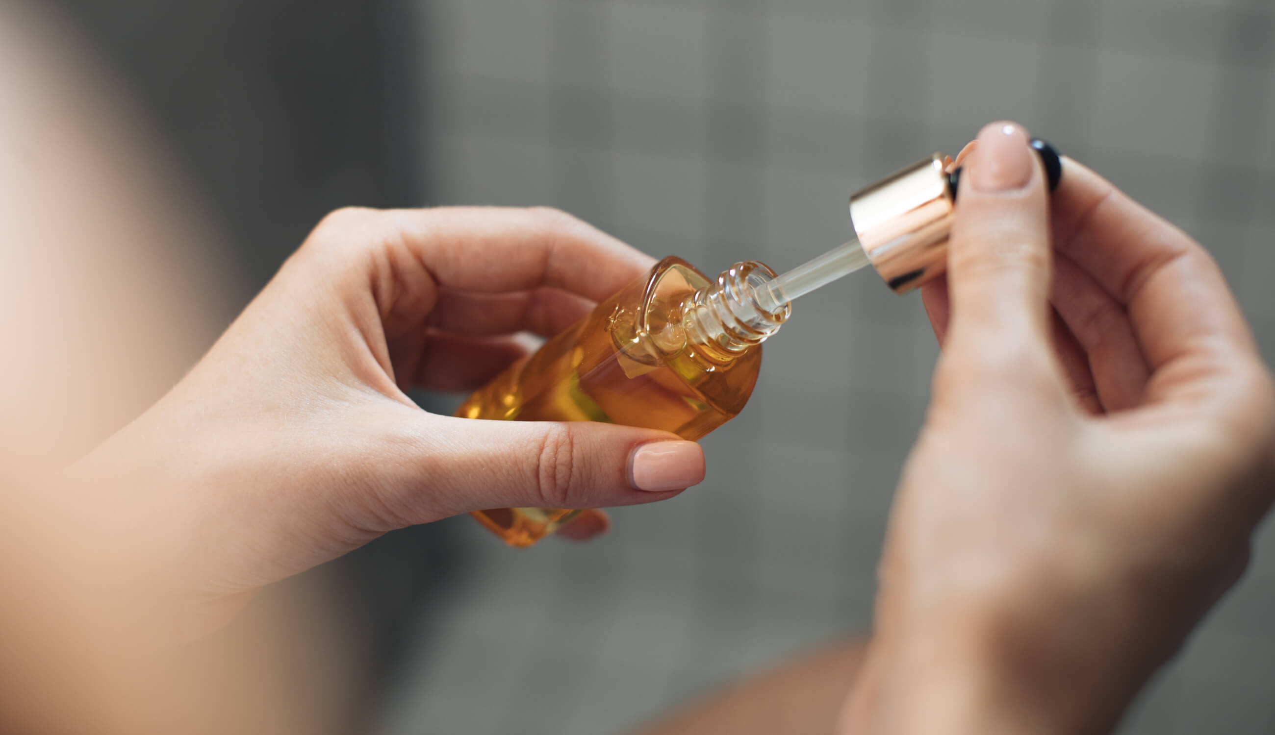 Woman using oil in bottle for acne-prone skin
