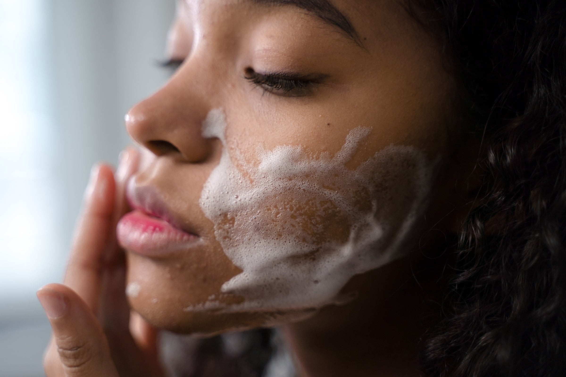 Close up shot of woman using foaming cleanser on her face