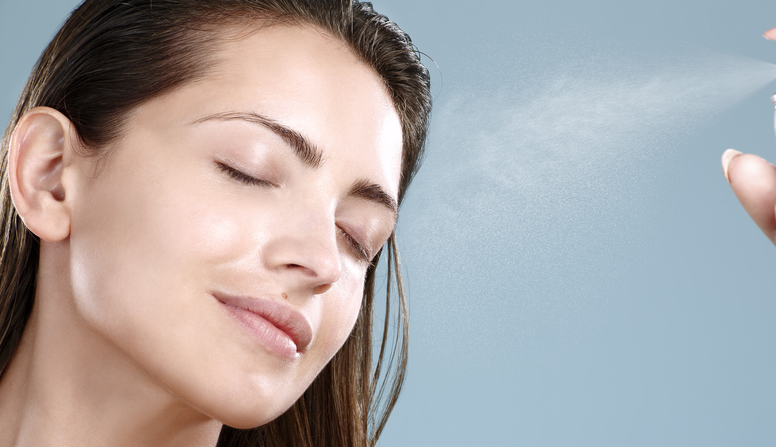 Woman spraying rose water on her face.jpg